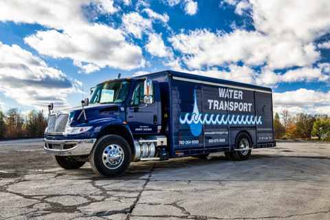 Navy blue Water Transport box truck for bottled water routes, parked on a paved yard