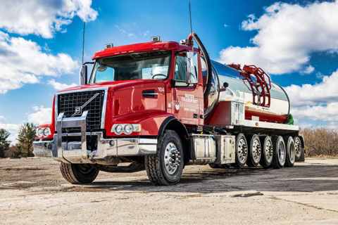 Red Water Transport Energy Services tanker truck with a hose reel on the side