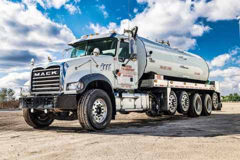 White Mack tanker truck lettered for Water Transport, side and front view
