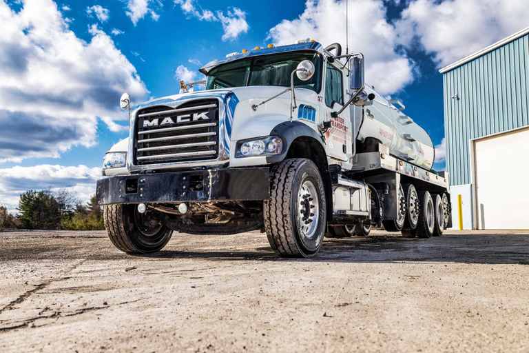 Front of a white Mack water tanker with a multi-axle trailer behind the cab